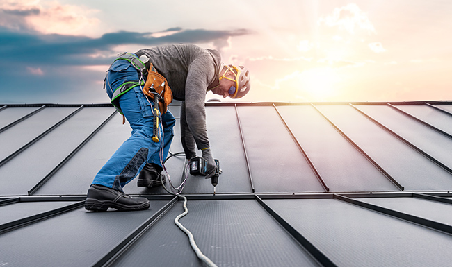 professional roofer is installing metal panels on a steep residential roof, showcasing the installation quality