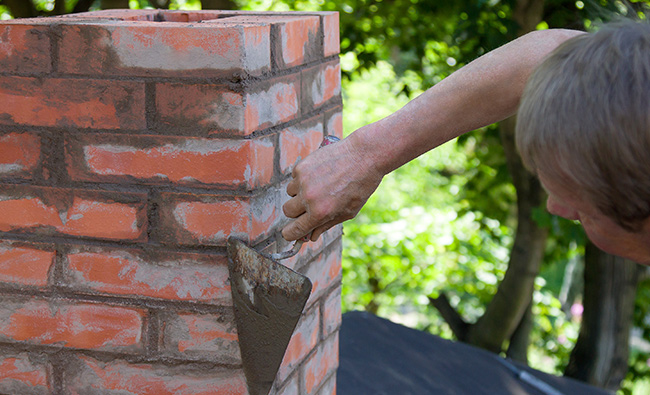 roofer sealing brick and mortar cracks around chimney